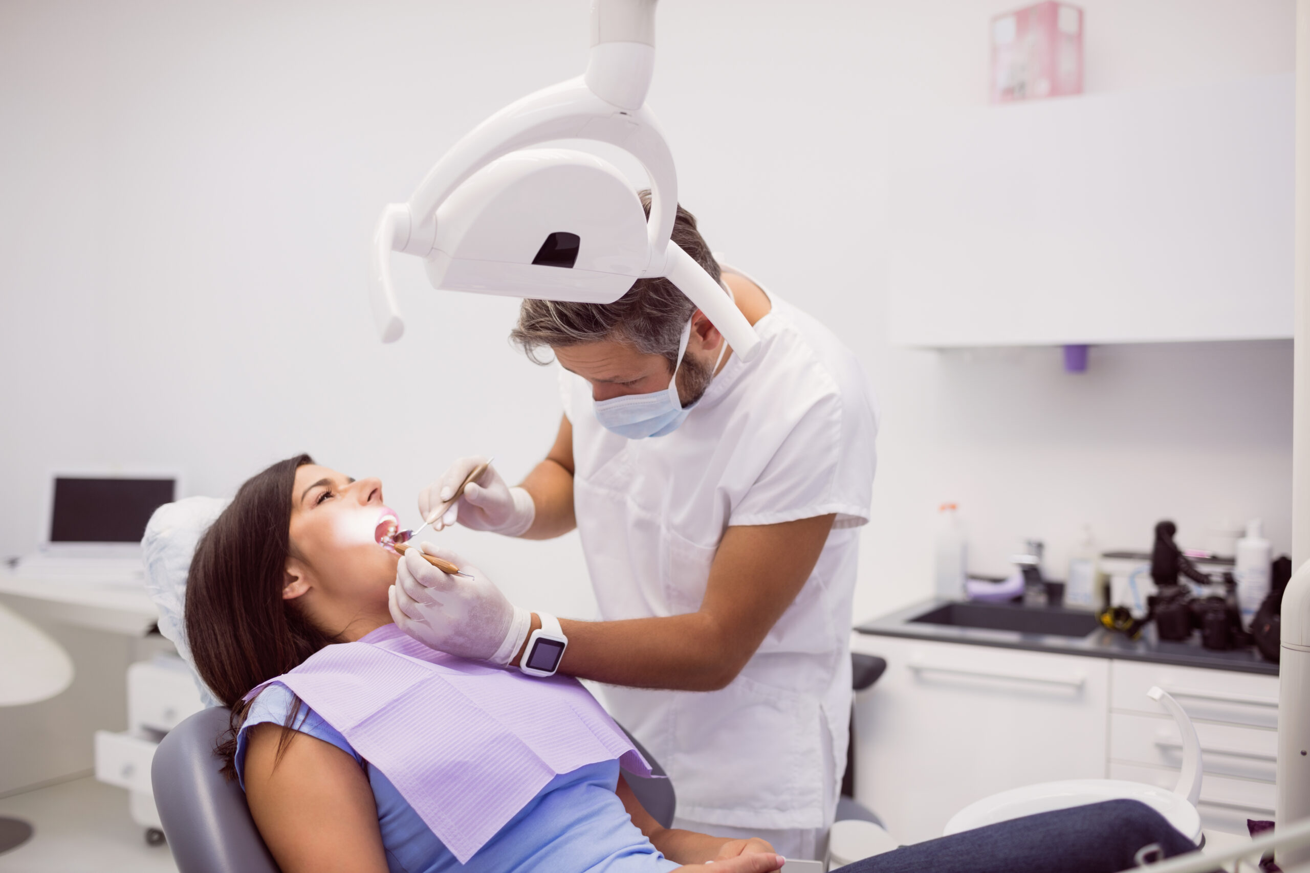 Dentist examining female patient teeth in clinic