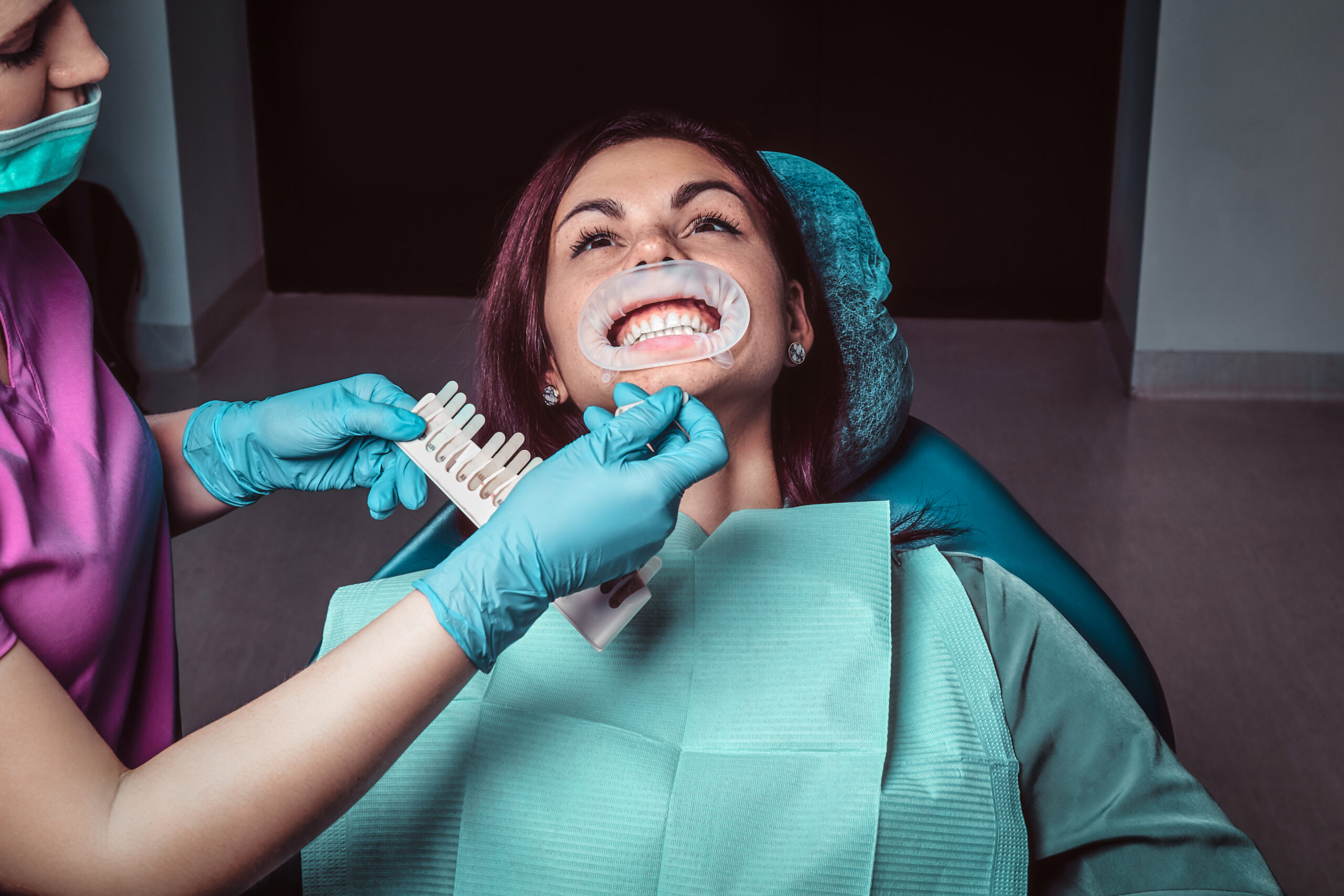 A woman dentist checks the level of teeth whitening in the dentist office.